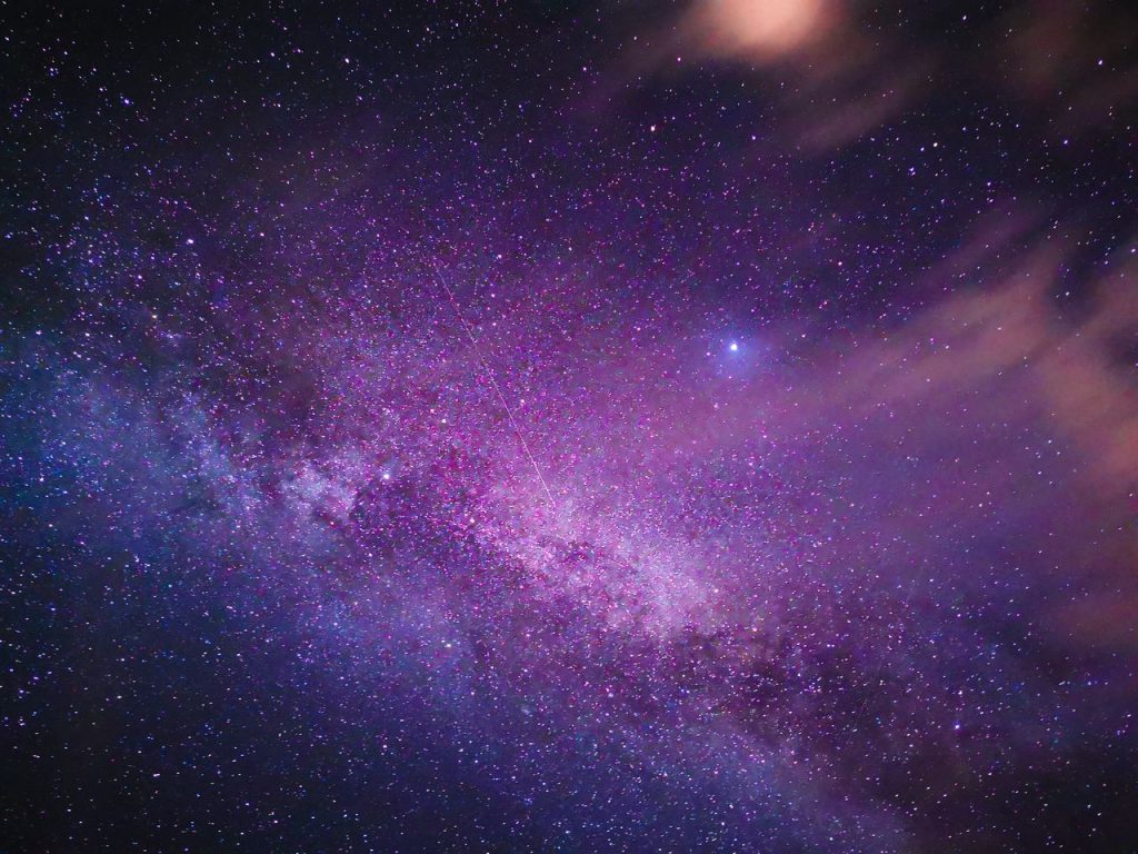 Purple-hued Milky Way galaxy with stars and nebula in a vast night sky.