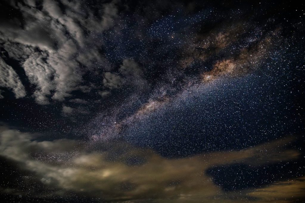 A breathtaking photo capturing the Milky Way galaxy with stars and clouds in a dark, starry sky.
