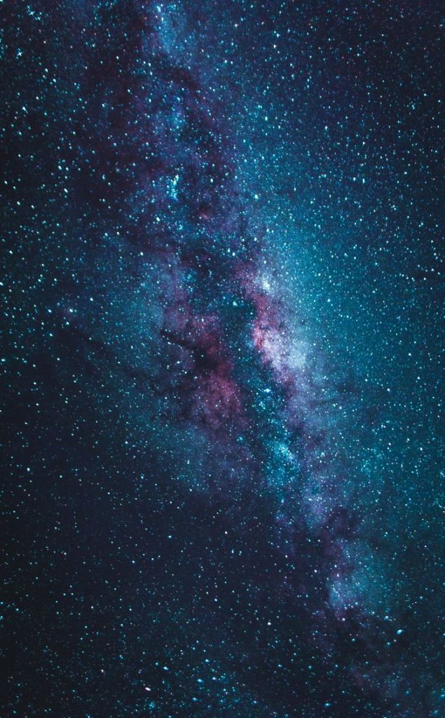 Stunning vertical view of the Milky Way galaxy in blue and purple hues under a starry night sky.
